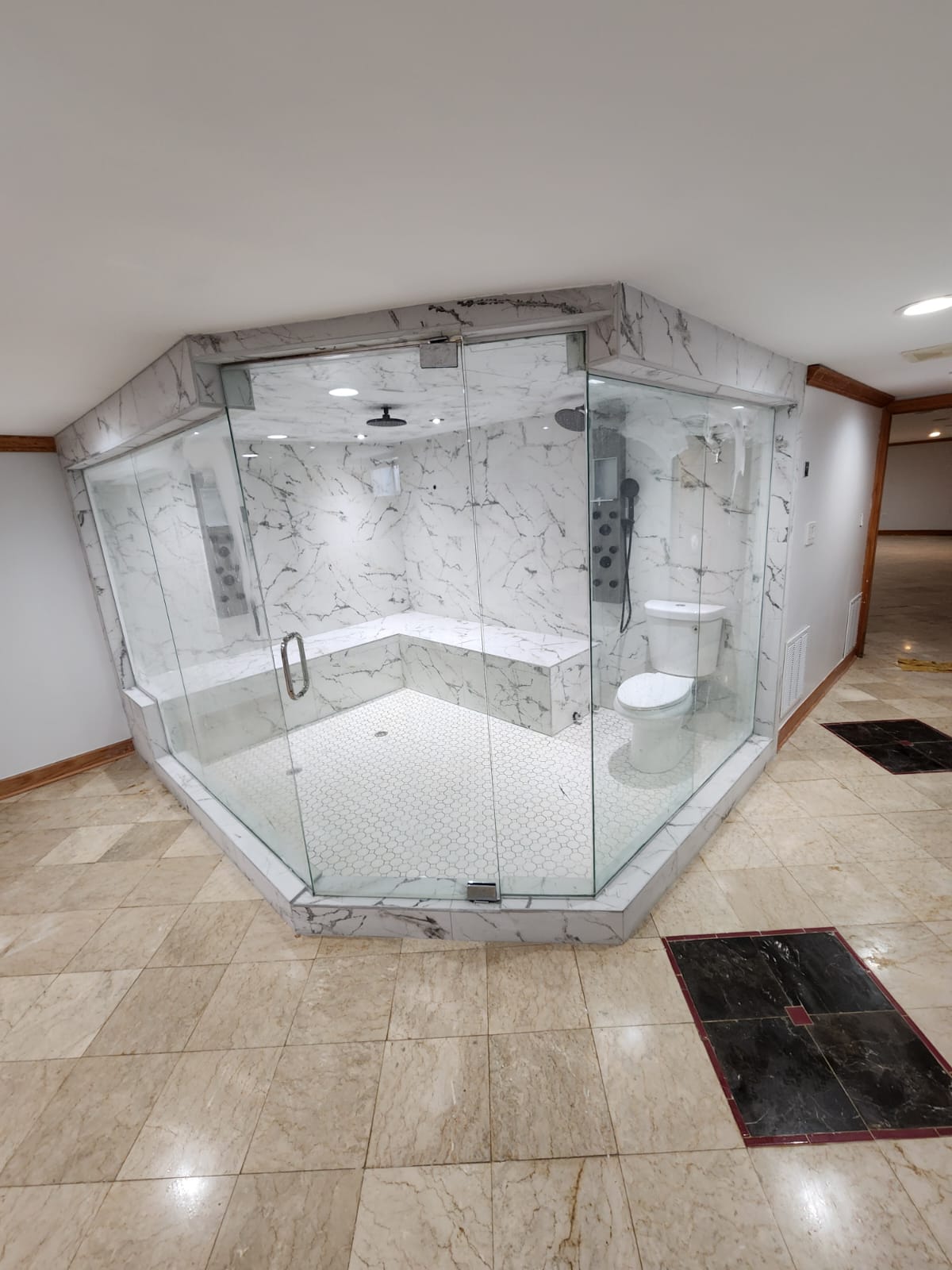 Large white marble glass steam shower with bench seating in a spacious remodeled bathroom.