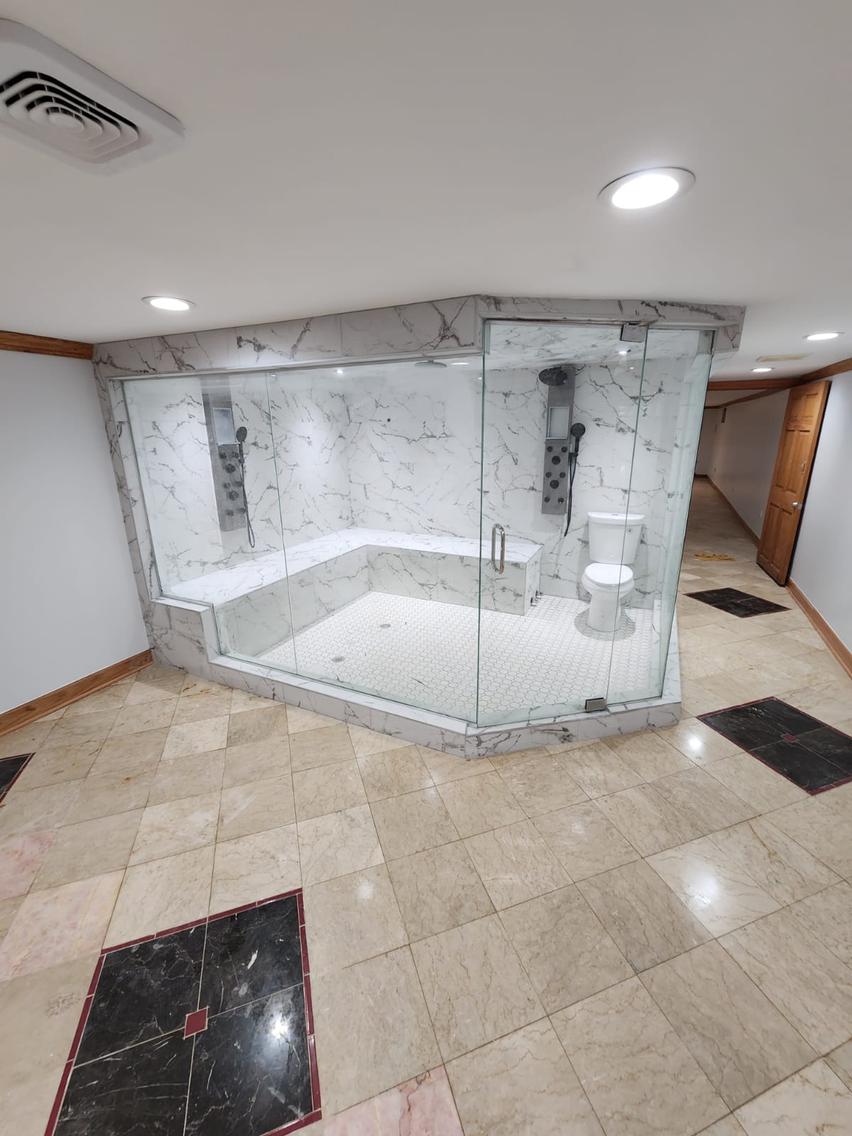 White marble walk-in shower with dual shower heads and travertine floor in a large bathroom.