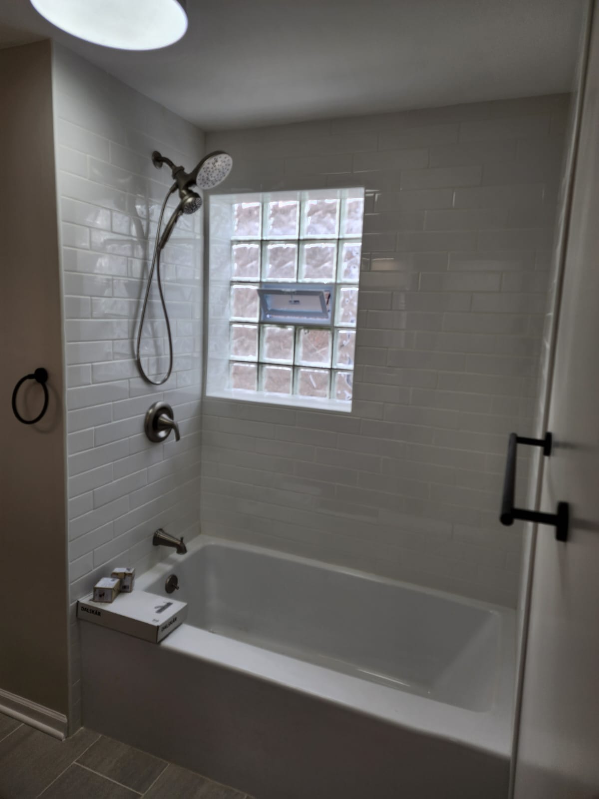 White subway-tile tub and shower surround with a glass-block window.